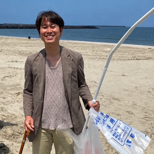 佐渡の海岸で,ごみ拾いの道具とごみ袋を持っている様子
